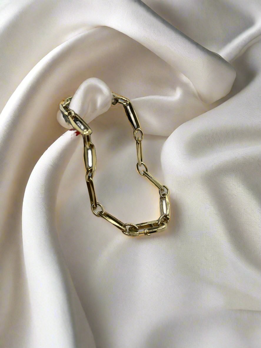 De vintage gouden armband 14k closed forever 7.7gr van Juwelier van der Kooij is elegant gedrapeerd over roomwit satijn en heeft een ovaal schakelontwerp en een groot wit parelaccent. Dit zorgt voor een prachtig contrast tussen de metaalachtige glans en de zachte textuur. Een prachtige aanvulling op elke vintage sieradencollectie.