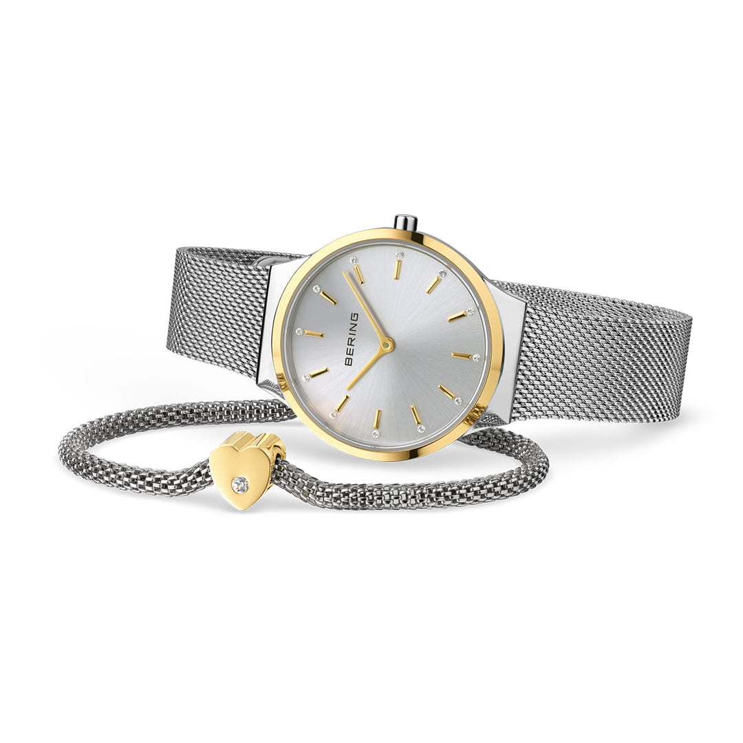 Berings 12131-014-GWP heeft een zilveren polshorloge met een metalen mesh band, minimalistische zilveren wijzerplaat, quartz uurwerk en gouden uurmarkeringen en wijzers. Het wordt geleverd met een bijpassende zilveren armband versierd met een gouden hartbedel en saffierglas juweeldetails.