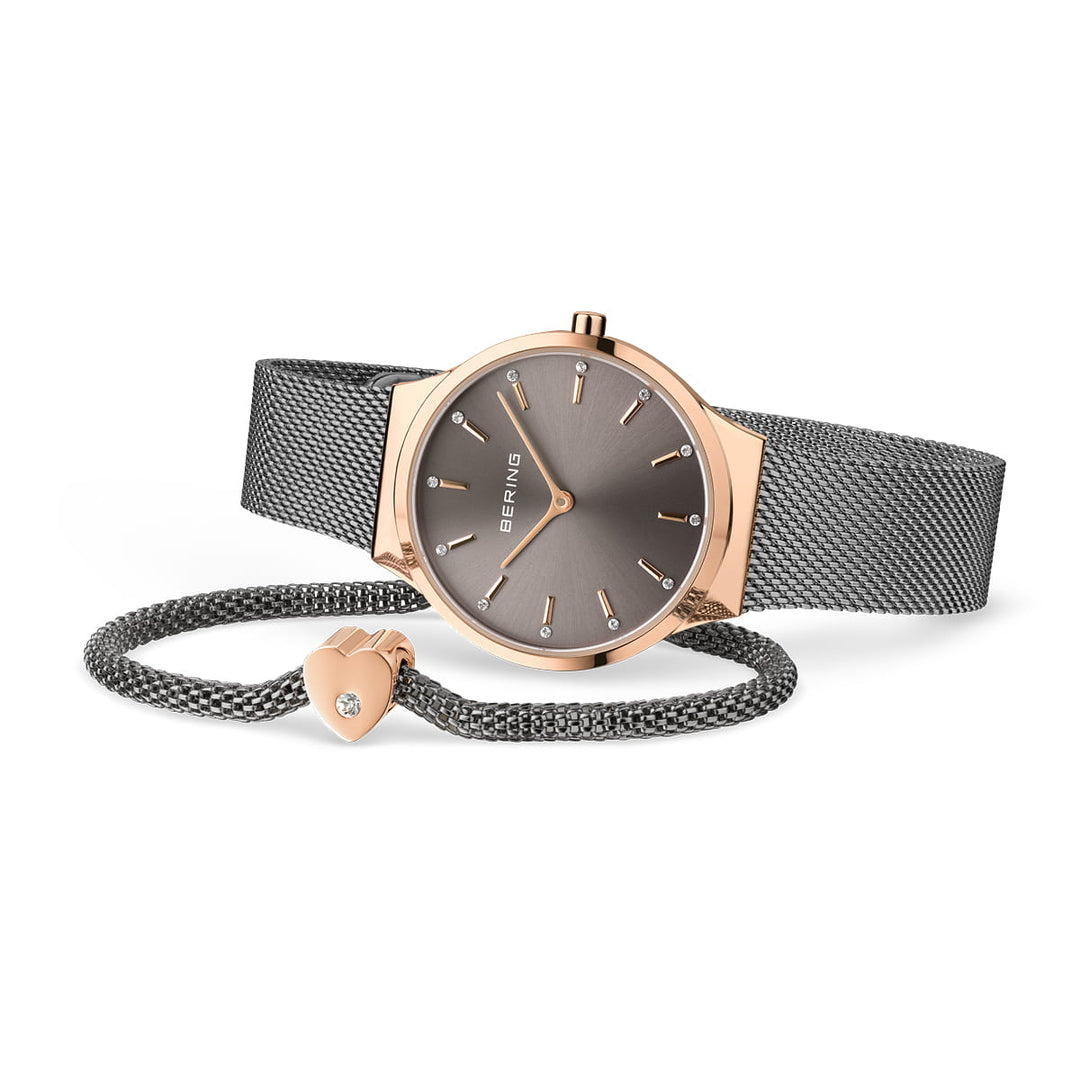 De Bering 12131-339-GWP is een chique quartzhorloge met een grijze Milanese band en roségouden kast, met een strakke grijze wijzerplaat met minimalistische gouden markeringen. Het wordt geleverd met een bijpassende armband met een hartvormige bedel versierd met een klein kristal.