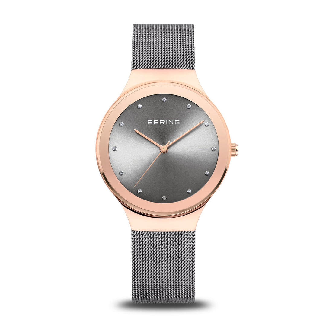 Het elegante Bering dameshorloge 12934-369 heeft een roségouden kast, een minimalistische grijze wijzerplaat met zilveren puntmarkeringen, BERING op de wijzerplaat, een Quartz-uurwerk en een bijpassende grijze mesh-band.