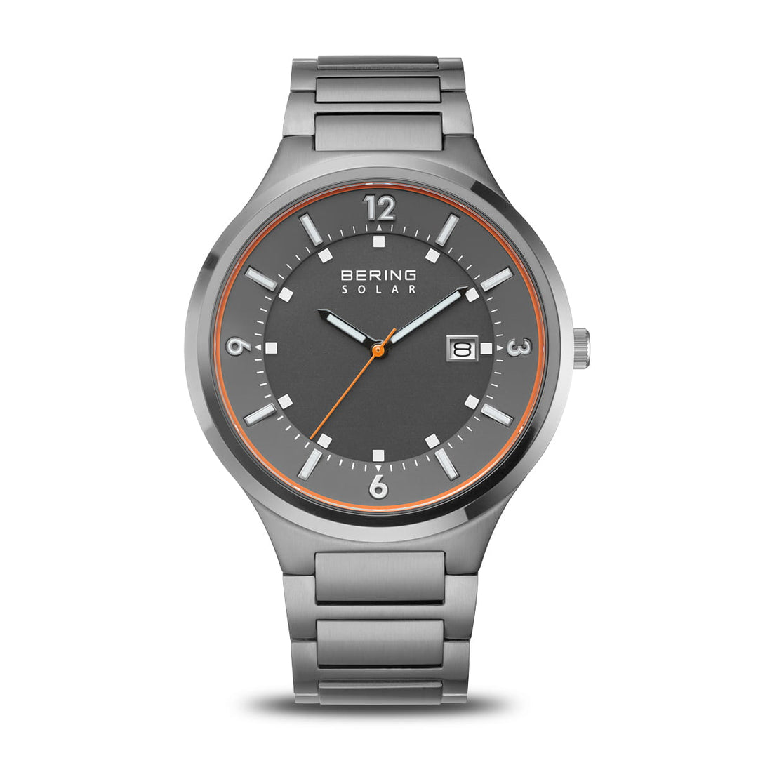 Het Bering 14442-777 horloge heeft een gepolijste zilveren metalen schakelband, een donkergrijze wijzerplaat met witte uurmarkeringen, oranje accenten, Saffierglas bescherming, Bering Solar opschrift en datumweergave.