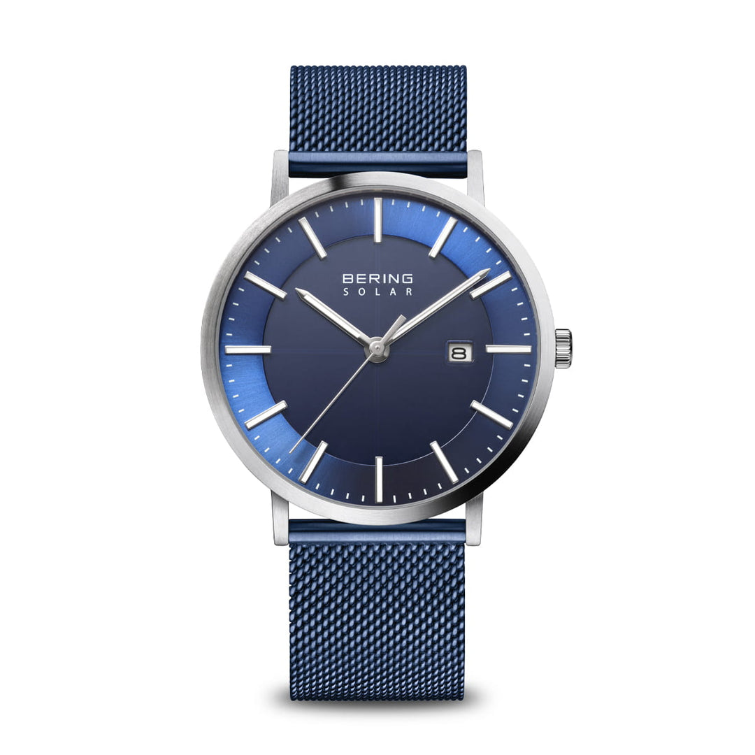 Het Bering 15439-307 horloge heeft een blauwe mesh band, een wijzerplaat van saffierglas met zilveren uurmarkeringen en wijzers en een datumvenster op 3 uur met het elegante opschrift Bering Solar.