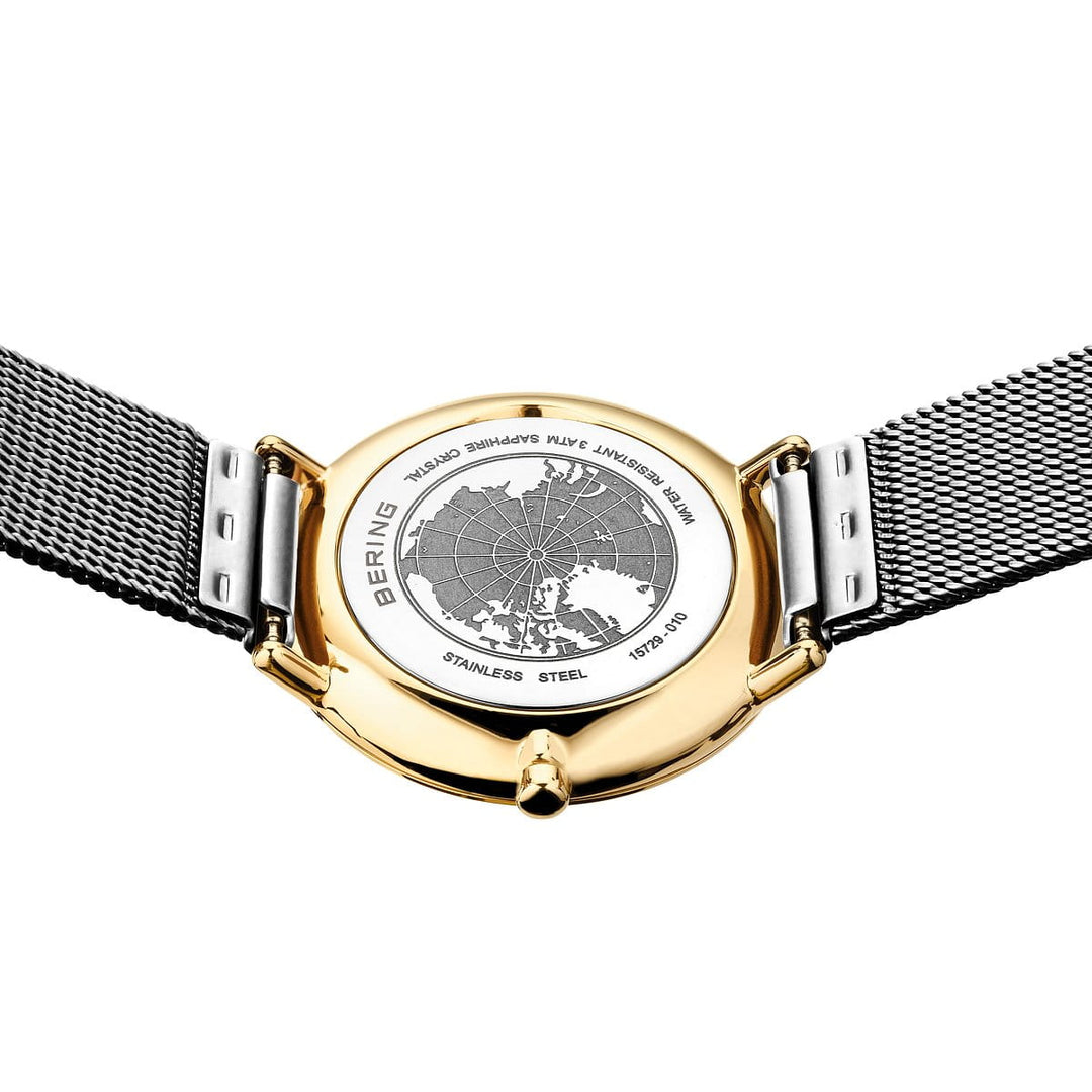 Op de afbeelding is de onderkant van een Bering Dameshorloge 15729-010 te zien met een kast van roestvrij staal van goud en zilver, een gegraveerde kaart en een strakke, zilveren mesh-band met de inscriptie BERING, STAINLESS STEEL en plaatsnamen zoals ISLANDS, PLAINS, LYKE. Dit alles toont de precisie van Quartz-technologie.