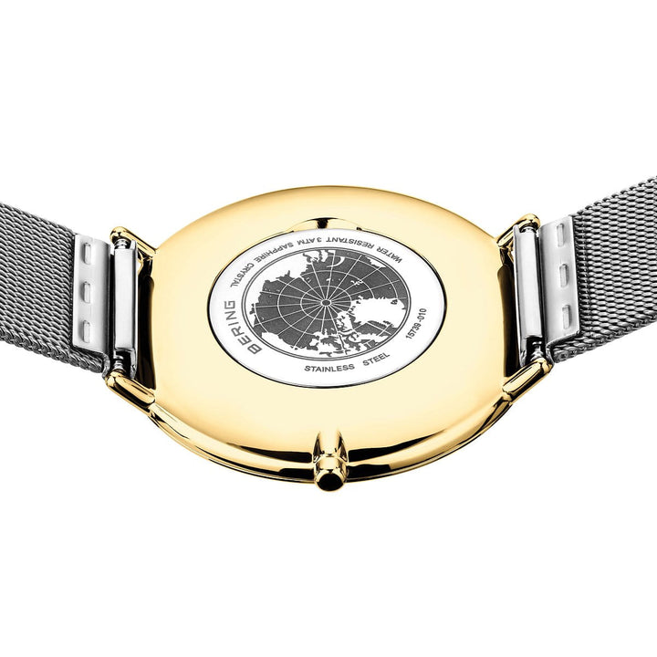 De afbeelding toont de achterkant van het Bering dameshorloge model 15739-010 met een roestvrijstalen kast en mesh band, met een elegant gegraveerd wereldkaartontwerp en teksten met onder meer Bering, Concepts en Stainless Steel, wat een tijdloze elegantie uitstraalt.