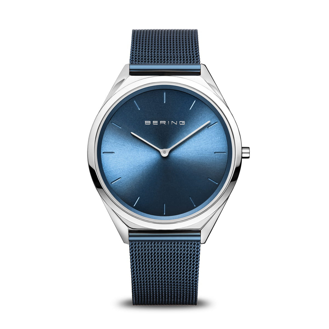 Het Bering unisex horloge (17039-307) heeft een strak design met een metallic zilveren kast, blauwe sunray wijzerplaat, minimalistische uurmarkeringen en zilveren wijzers. Het beschikt over saffierglas bescherming en een blauwe mesh band, met BERING prominent op de wijzerplaat.