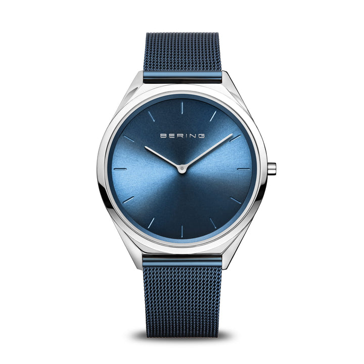 Het Bering unisex horloge (17039-307) heeft een strak design met een metallic zilveren kast, blauwe sunray wijzerplaat, minimalistische uurmarkeringen en zilveren wijzers. Het beschikt over saffierglas bescherming en een blauwe mesh band, met BERING prominent op de wijzerplaat.