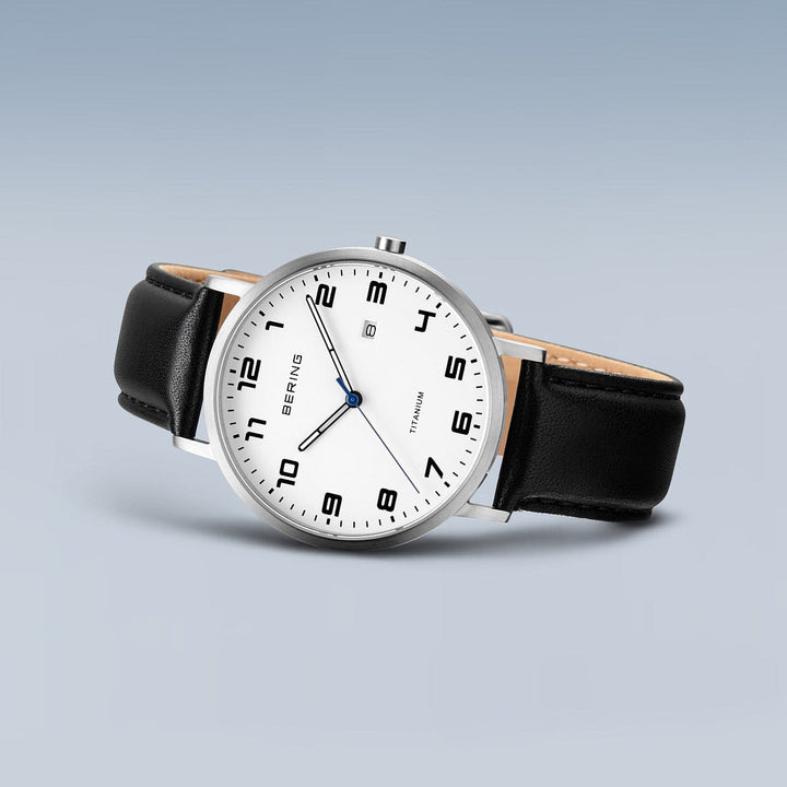 Het Bering heren horloge 18640-404 heeft een minimalistisch design met een witte wijzerplaat, zwarte Arabische cijfers en een datumvenster op 3 uur. Het heeft een zilveren titanium kast en een zwarte leren band, aangestuurd door een precisie Quartz uurwerk.