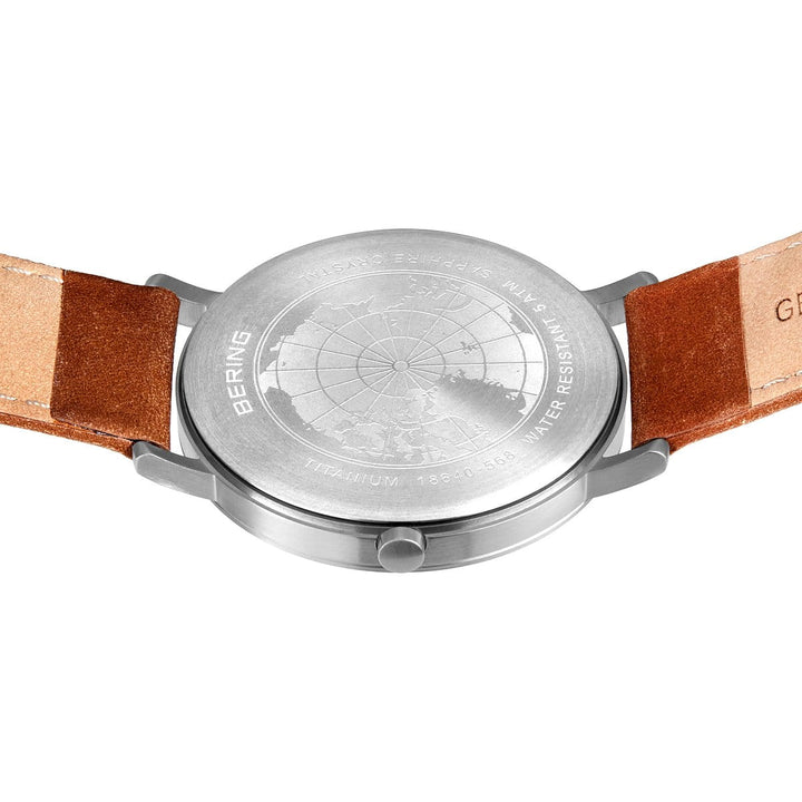 De afbeelding toont de onderkant van een zilveren Bering heren horloge (18640-568) met een gestikte leren band. De titanium horlogekast toont een wereldkaart en gravures zoals BERING, TITANIUM en WATER RESISTANT.
