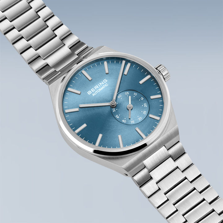 Het Bering heren horloge 19441-Charity is een zilveren horloge met een metalen band, een blauwe wijzerplaat, bescherming van saffierglas, slanke markeringen en wijzers en een kleinere subwijzerplaat bij 4 uur.