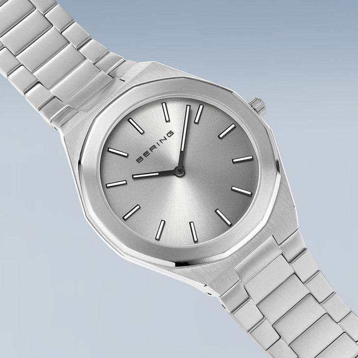 Het Bering herenhorloge (19641-700) heeft een minimalistisch design met een zilveren wijzerplaat, metalen band, dunne zwarte uurmarkeringen en wijzers die worden aangestuurd door een quartz uurwerk. Het heeft krasbestendig saffierglas en een lichtblauwe gradiëntachtergrond.