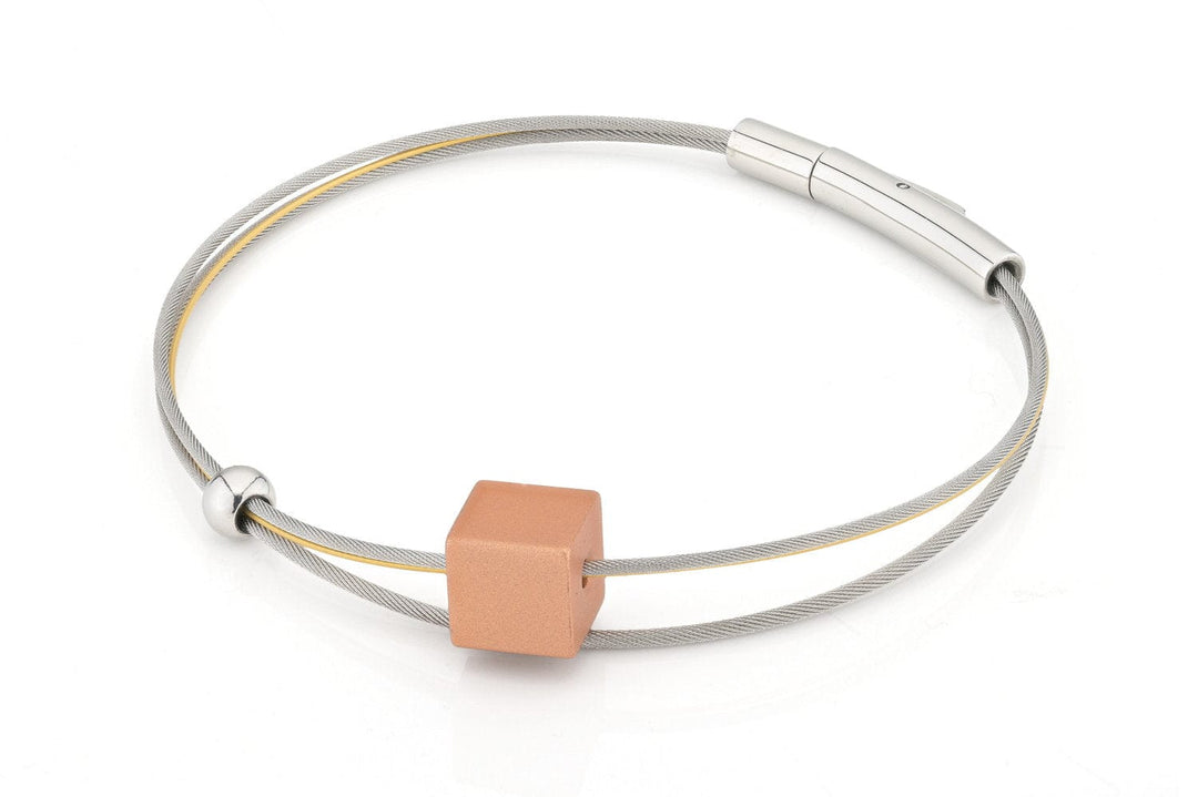 De A259O-18 van Clic Creations is een minimalistische armband met een zilveren draad versierd met een vierkante perzikkleurige kraal en een kleine zilveren kraal. De cilindrische sluiting maakt het eenvoudige maar elegante ontwerp compleet.