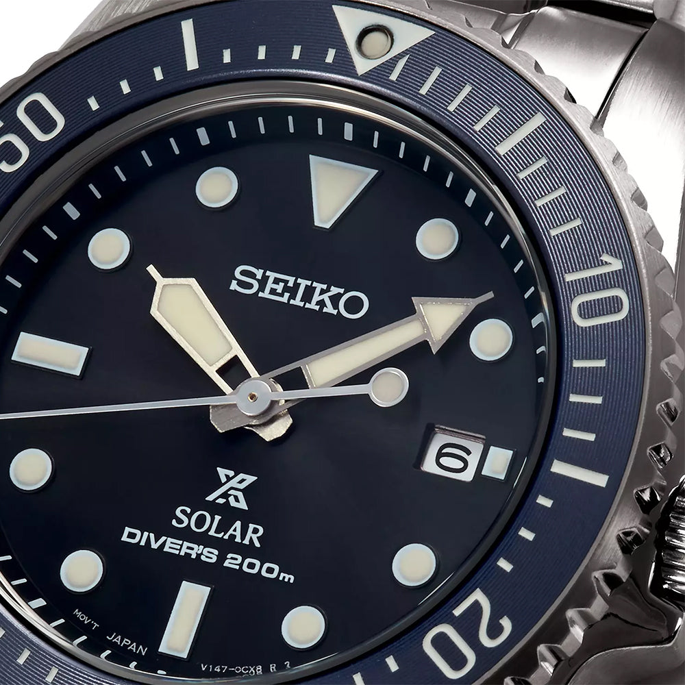Close-up van het Seiko Prospex heren horloge SNE569P1, met een blauwe wijzerplaat met witte markeringen. Het beschikt over een 3-uurs datumvenster, lichtgevende wijzers, draaibare lunette en wordt op zonne-energie aangestuurd met Solar-technologie. Waterbestendig tot 200 meter.