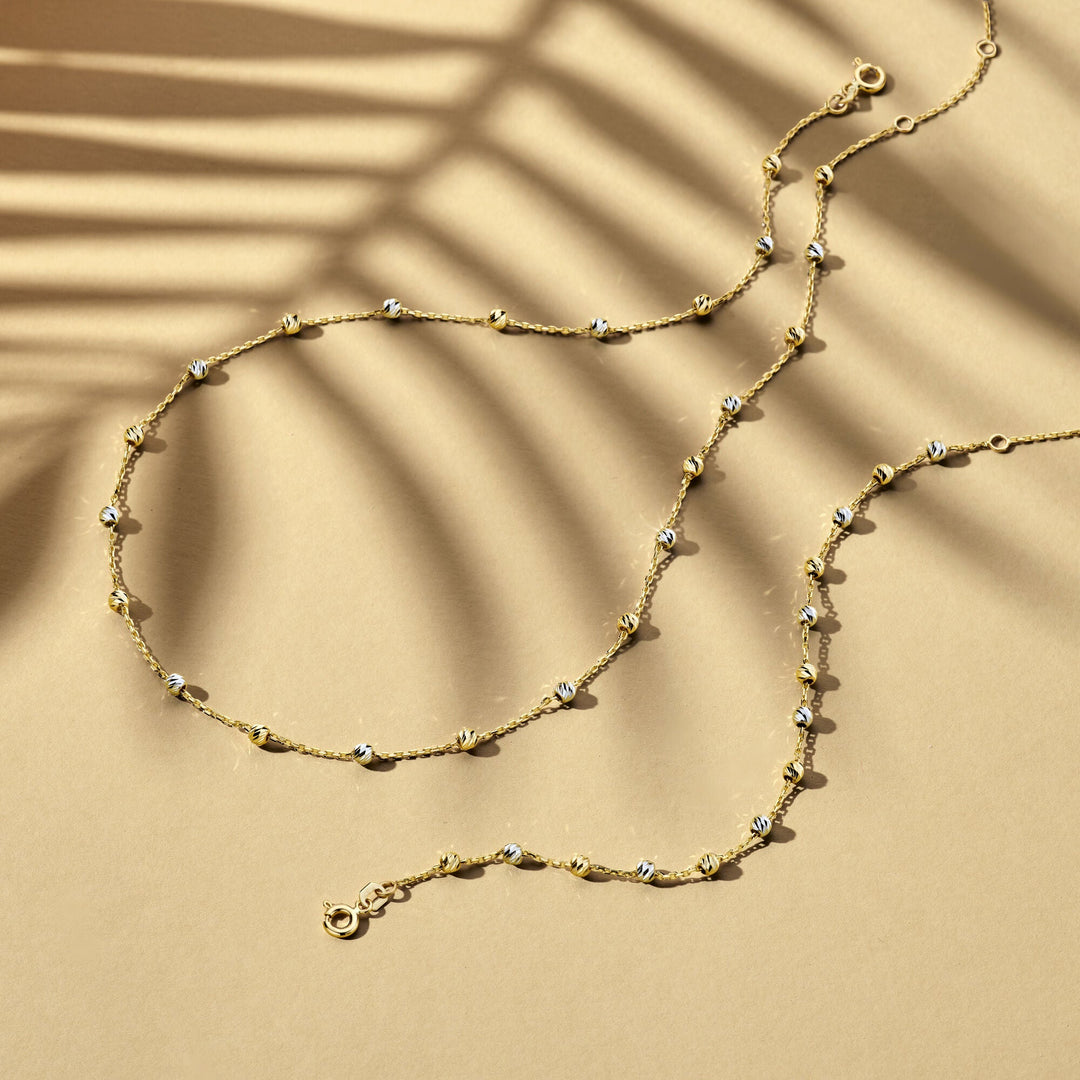 De Van der Kooij Collectie Gouden armband dames bolletjes gediamanteerd 14K bicolor, met wit- en geelgoud details en diamanten accenten, rust elegant op een tan oppervlak voor een verfijnde look.