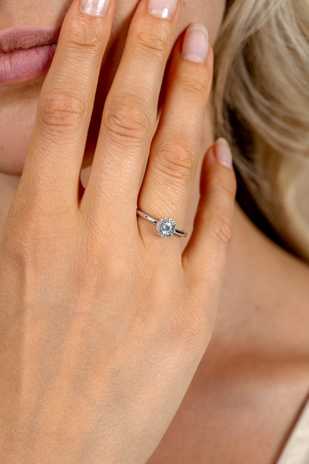 Een close-up van een lichtgekleurde vrouwenhand die de Zinzi Ring zilver ZIR2697 van Zinzi draagt, met een grote, ronde, glinsterende witte zirkonia op haar ringvinger en haar nagels zijn netjes verzorgd, lichtroze.