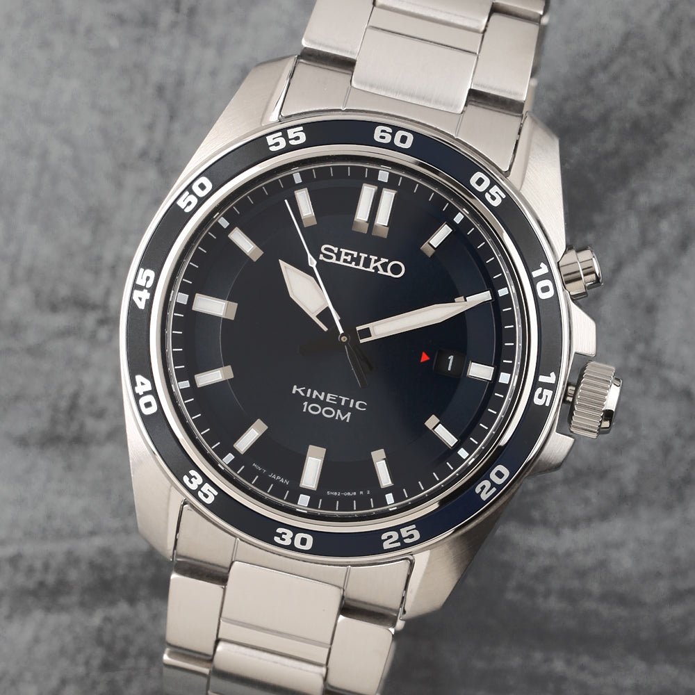 De Seiko herenhorloge SKA785P1 heeft een Kinetic uurwerk, 10ATM waterdichtheid en een roestvrijstalen band. Het heeft een zwarte wijzerplaat met witte uurmarkeringen en een datumvenster op drie uur tegen een gestructureerde grijze achtergrond, wat zowel stijl als precisie biedt.