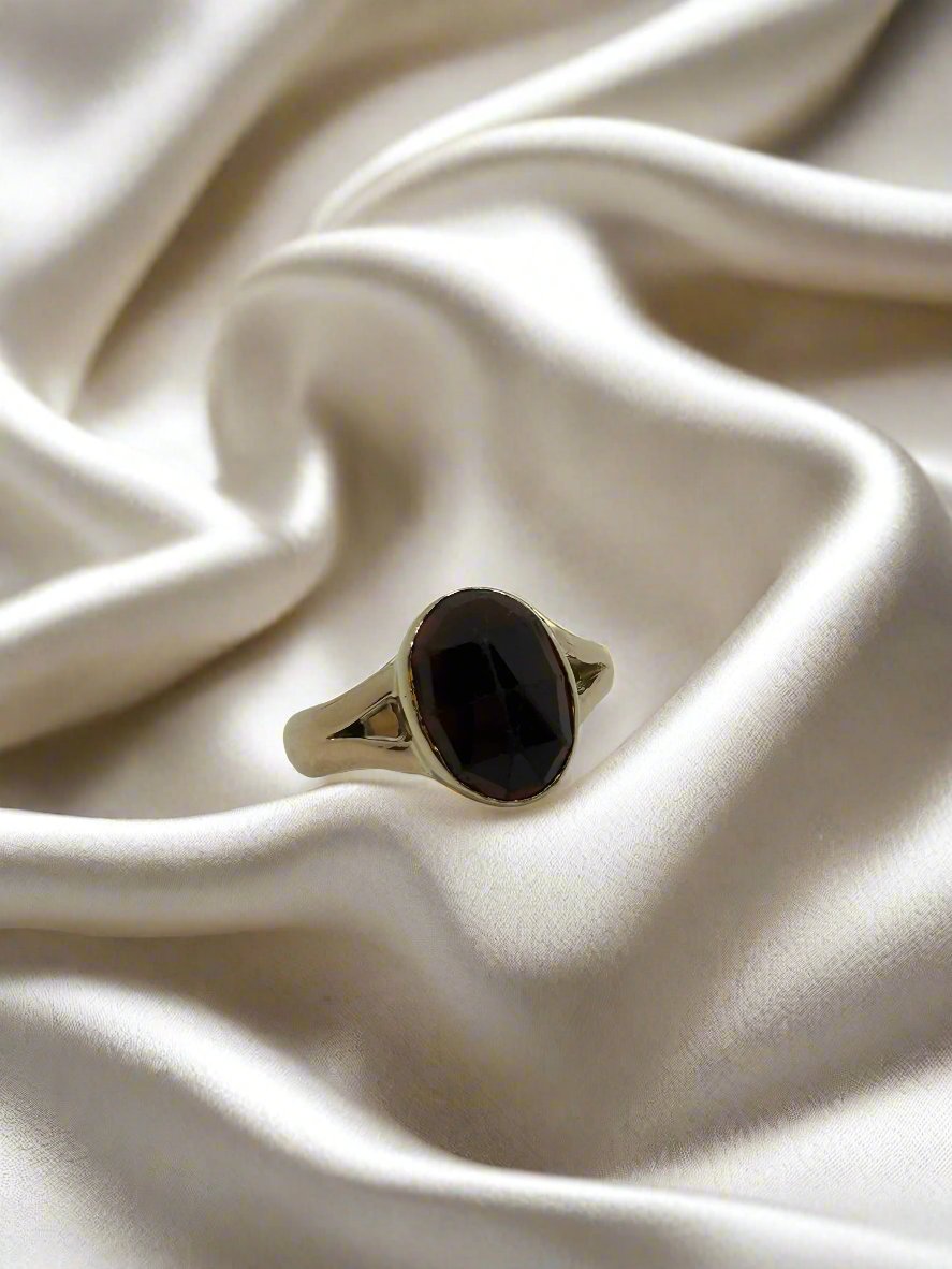 Vintage gouden ring van 14k met een ovale granaat, 5,5 gram, op een satijnen achtergrond.