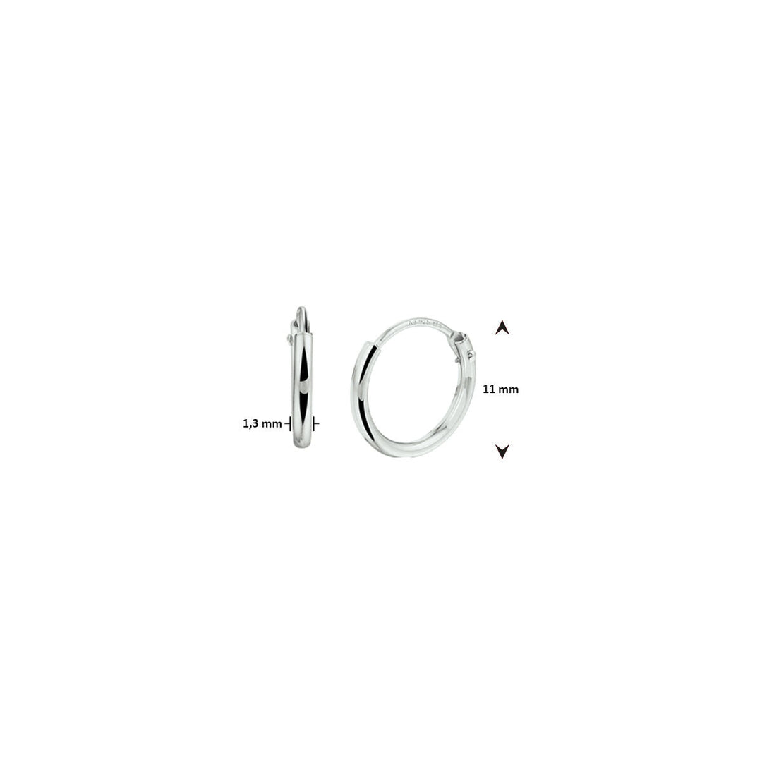 Twee oorringen 1,3 mm ronde buis zilver wit van Van der Kooij Collectie zijn te zien: één van voren en één van opzij. Pijlen tonen de afmetingen: 11 mm doorsnee, 1,3 mm dikte. De achtergrond is wit.