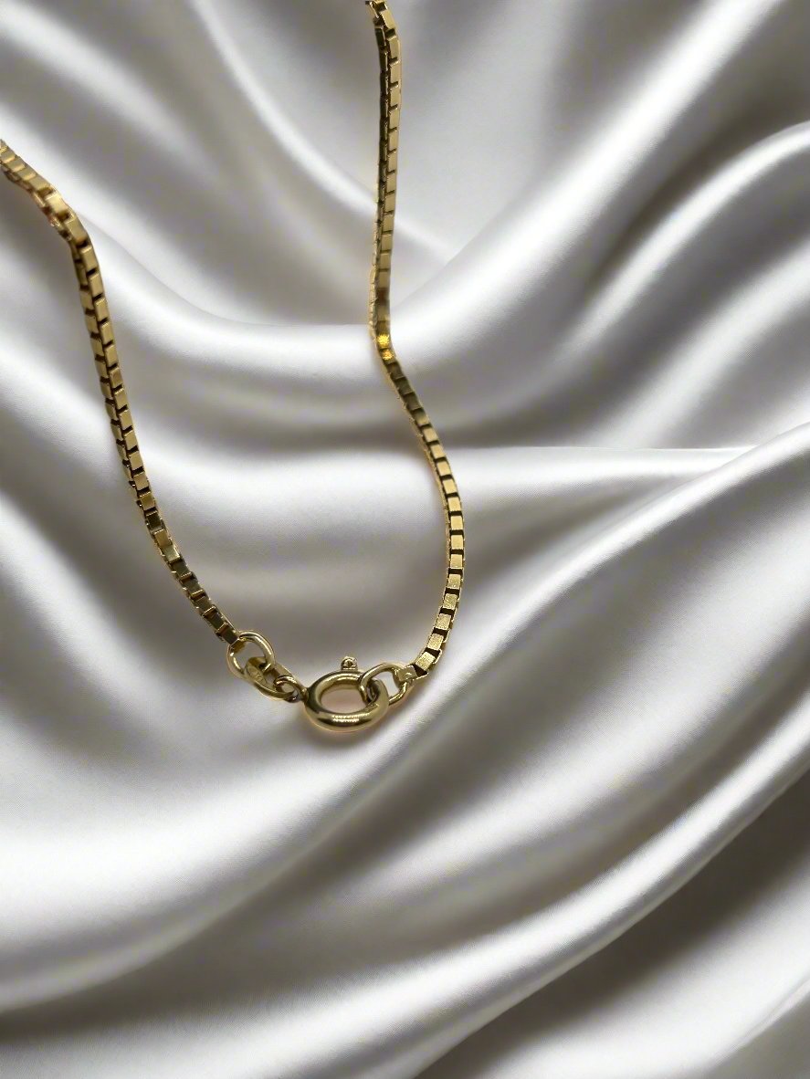 Een vintage gouden collier 52cm venetiaans 18k 10gr van Juwelier van der Kooij met sluiting rust elegant op glad wit satijn en straalt luxe en verfijning uit.