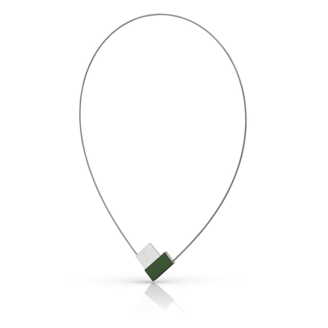 De Collier V-vorm Groen C150GR van CLIC Creations is een minimalistische ketting met een dunne metalen draad in een traanvorm. Het heeft een geometrische hanger met afwisselende groene en zilveren segmenten, wat een moderne touch toevoegt aan het unieke ontwerp. Handgemaakt in Nederland, het werpt subtiele reflecties naar beneden.