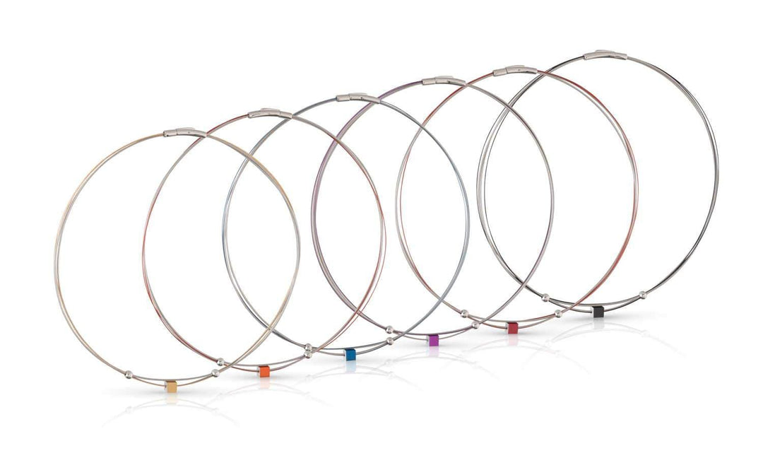 Zeven metalen draad sleutelhangers van CLIC Creations, gemaakt van chirurgisch staal, tonen sluitingen in geel, oranje, rood, paars, blauw, groen en zwart. Getoond op een witte achtergrond met kleine gekleurde kubussen voor charme; één toont het Collier Klein Kubusje Rood C230R ontwerp.