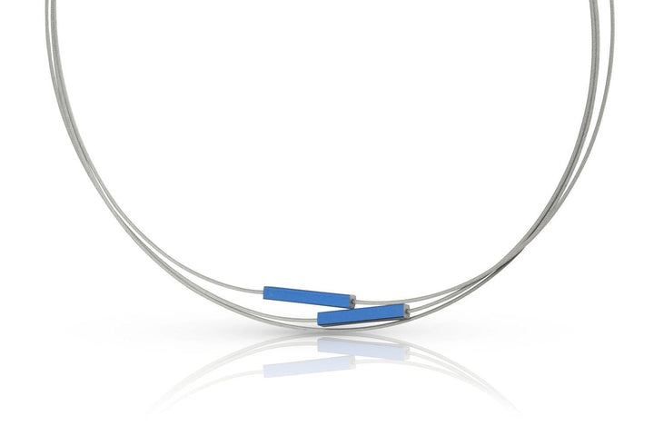 De Collier Staafjes Blauw C243B van CLIC Creations is een minimalistische chirurgisch stalen ketting met drie dunne blauwe rechthoekige hangers. Hij schittert elegant terwijl zijn opgerolde zilveren vorm reflecteert op een witte achtergrond.