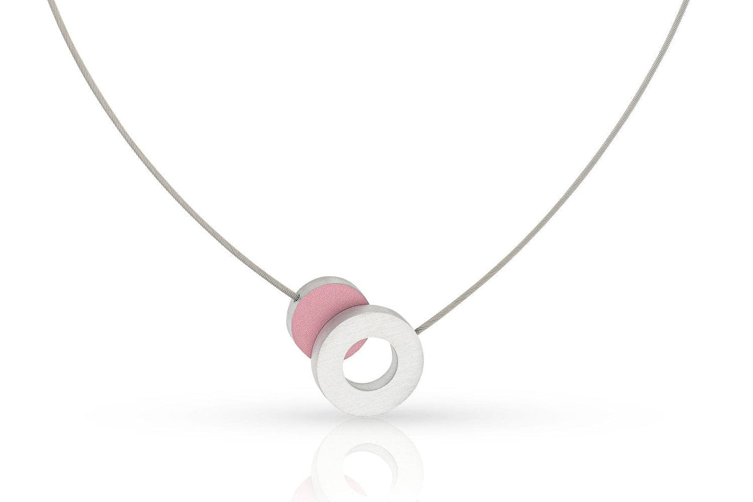 De Collier Gekleurd rondje en een ring C265R van CLIC Creations heeft een minimalistisch design met een dun koord en een moderne, elegante hanger. De ronde hanger bevat in elkaar grijpende schijven: één getextureerd roze en één wit met een hol midden.
