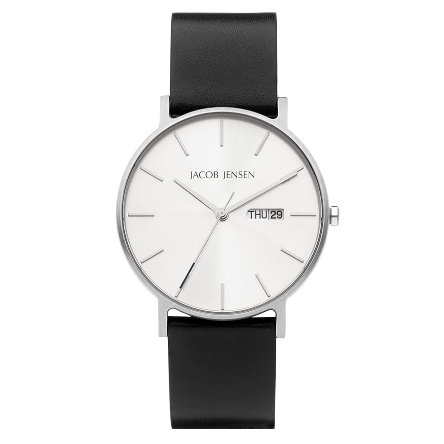 De Jacob Jensen 160 is een minimalistisch quartz polshorloge met een witte wijzerplaat met zilveren markeringen en wijzers. Het bevat een klein datumvenster met THU 29, heeft duurzaam saffierglas en is uitgerust met een strakke zwarte leren band.