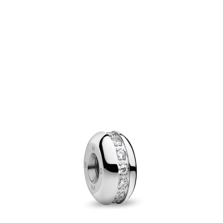 Een zilveren charm spacer met een ronde vorm, versierd met heldere edelstenen, weerspiegelt de elegantie van het Bering dameshorloge. De schittering ervan steekt af tegen een eenvoudige witte achtergrond. Product: 12927-307-GWP van Bering.