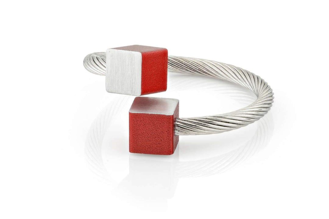 De Ring Kubusjes Rood R4R van CLIC Creations is een handgemaakte armband gemaakt in Nederland van chirurgisch edelstaal. Het heeft een zilveren twist design met rode en zilveren matte kubus uiteinden en reflecteert licht prachtig op witte oppervlakken. One size fits most.