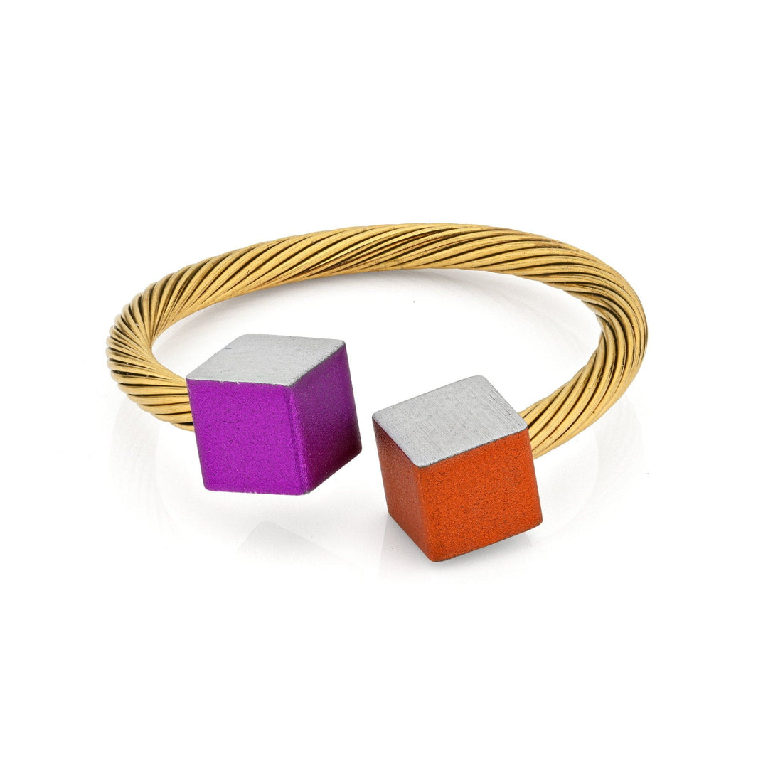 De Gouden Ring Kubusjes Oranje Paars RG4OP van CLIC Creations is een minimalistische armband van gedraaid gouddraad, met unieke oranje en paarse blokjes aan elk uiteinde, gemaakt van chirurgisch staal voor veerkracht en elegantie.