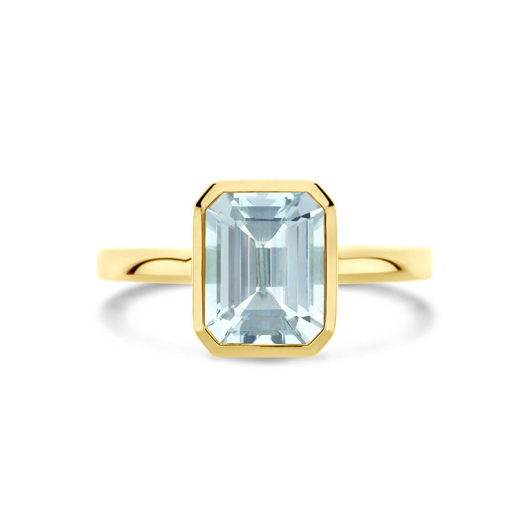 De ring aquamarijn 14K geelgoud van Van der Kooij Collectie heeft een rechthoekige, smaragdgeslepen aquamarijn in een strakke bezelzetting, tegen een witte achtergrond.