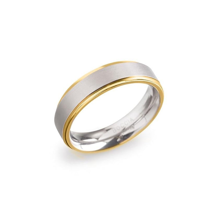 De Boccia Titanium Ring Bicolor 0134-05 heeft een matte zilveren kern met gepolijste gouden randen, waardoor de verfijnde tweekleurige stijl van Boccia op een witte achtergrond wordt benadrukt.