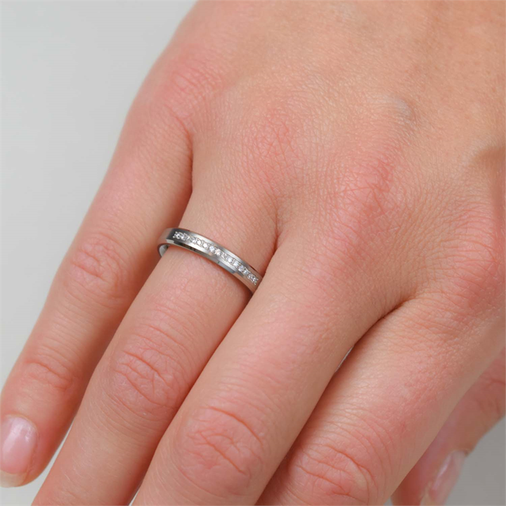 Een close-up van een hand die de Boccia Titanium Ring dia 15/0.075 - 0120-04 van Boccia draagt, met kleine ingebedde steentjes op de ringvinger tegen een effen achtergrond.
