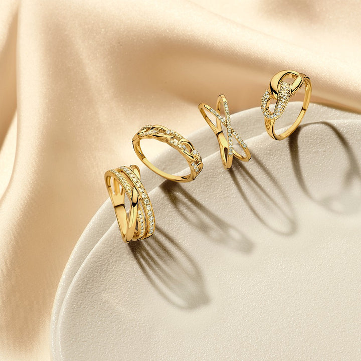 De Geelgouden Ring met Verbonden Schakels en Diamant van Excellent Jewelry schittert elegant op een lichtbeige ondergrond met satijnen stof - een 14 karaat luxe damesjuweel perfect gepresenteerd.