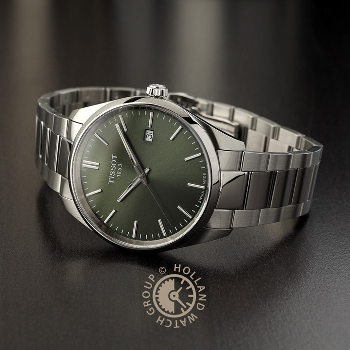 Een roestvrijstalen Tissot PR 100 herenhorloge met groene wijzerplaat, datumaanduiding op 3 uur en metalen schakelarmband rust op een donker oppervlak met het logo van Holland Watch Group.