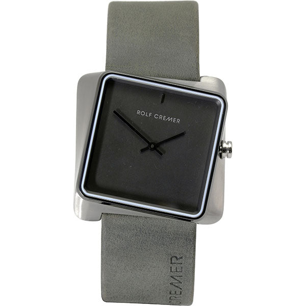 Het Rolf Cremer Horloge 501702 is een vierkant horloge met een grijze wijzerplaat, zilveren kast en minimalistische zwarte uur- en minutenwijzers. Het heeft een grijze leren band met reliëf ROLF CREMER bij de lugs, heeft een kroon op drie uur en wordt aangestuurd door een quartz uurwerk.