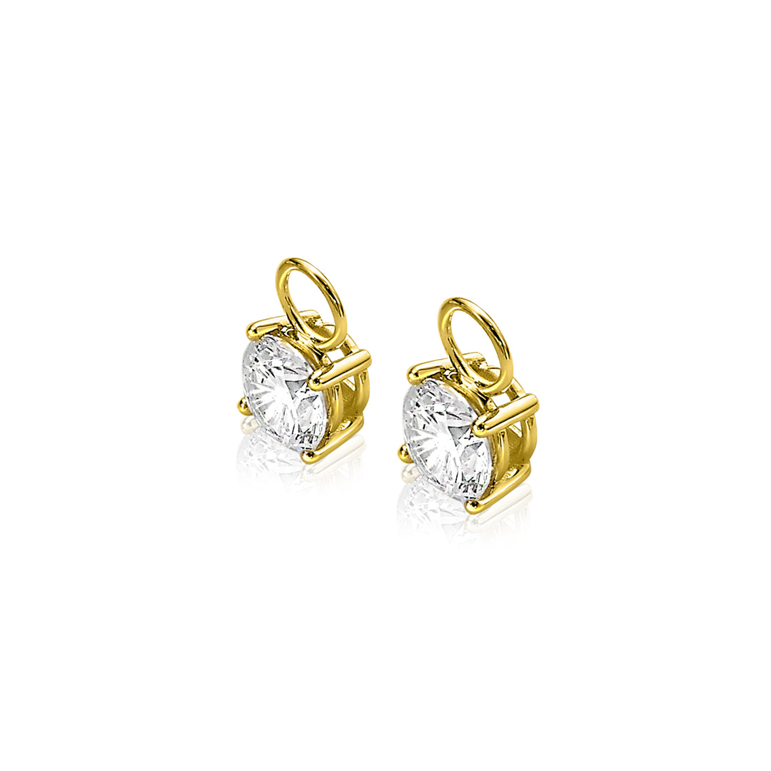 Twee Zinzi Oorbellen Goud Zgch143, met kleine ronde diamanten bedels met gouden pootjes en lusbevestigingen, zijn geplaatst tegen een witte achtergrond. Ze vangen prachtig het licht, waardoor de fijn geslepen diamanten elegant schitteren.